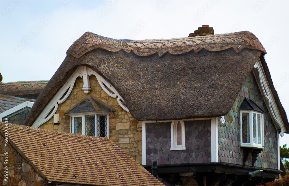 A close up image of a picturesque Thatched roof building featuring its old English style straw roof as well as its colorful stone decorated exterior. A close up image of a picturesque Thatched roof building featuring its old English style straw roof as well as its colorful stone decorated exterior.