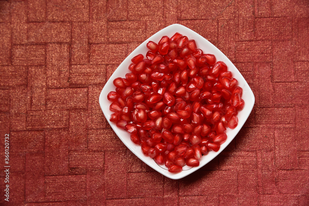 pomegranate seeds in a dish with textured background. pomegranate seeds in a dish with textured background.