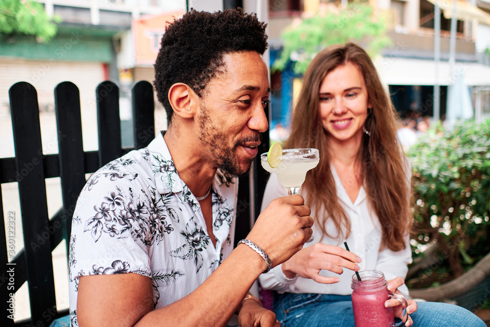 young interracial couple in love drinking a cocktail at the bar in summer young interracial couple in love drinking a cocktail at the bar in summer