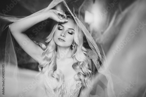 Monochrome portrait of sensuality and charming smiling young blondie. Beautiful sexy lady with long hair, and perfect make up dreaming with closed eyes. Concept of beauty. Morning of bride.