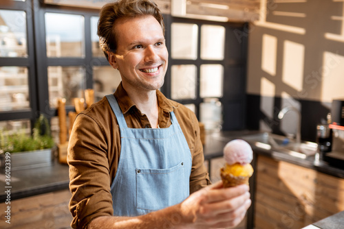 Φωτογραφία Portrait of a cheerful ice cream seller in working uniform holding ice cream in