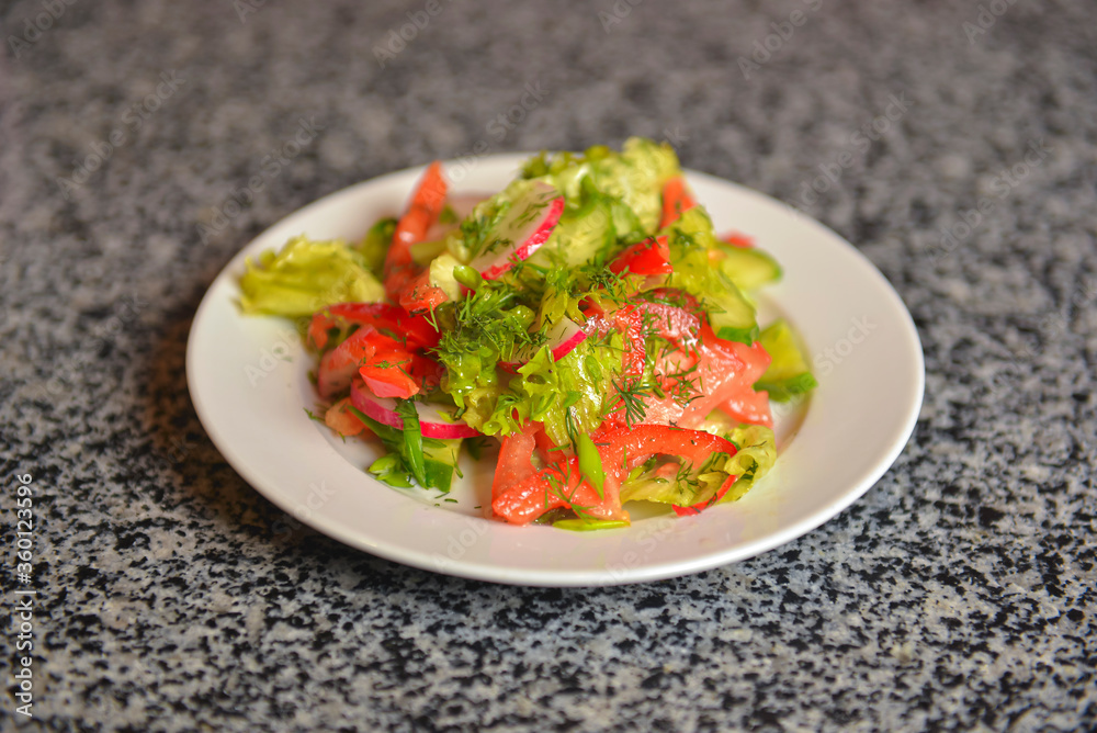 Vegetable salad with radishes,cucumber, sweet pepper and dill. Served in a white plate over grey textured table. Vegetable salad with radishes,cucumber, sweet pepper and dill. Served in a white plate over grey textured table.
