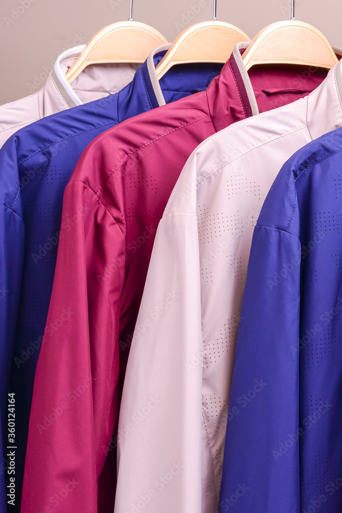 Row of many different colorful hoodie jackets, sport jackets for men and women. Seasonal clothing in store on sale.