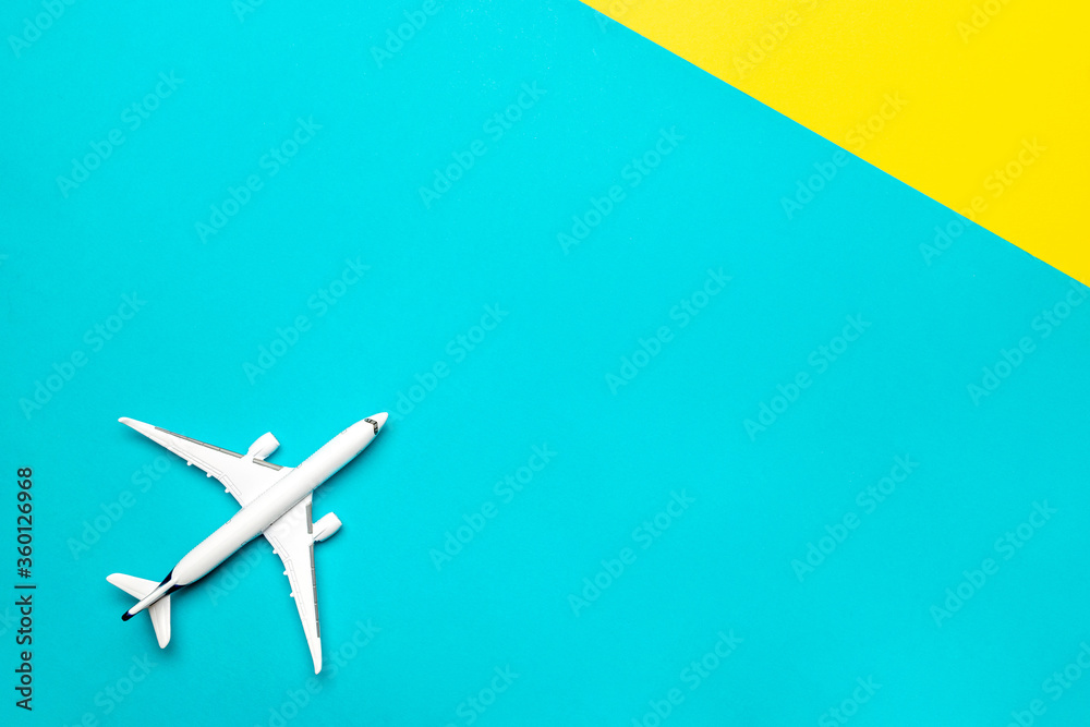 Plane banner. White toy airplane on bright blue and yellow background. Flight in sky, aircraft fly in air travel concept. Plane banner. White toy airplane on bright blue and yellow background. Flight in sky, aircraft fly in air travel concept.