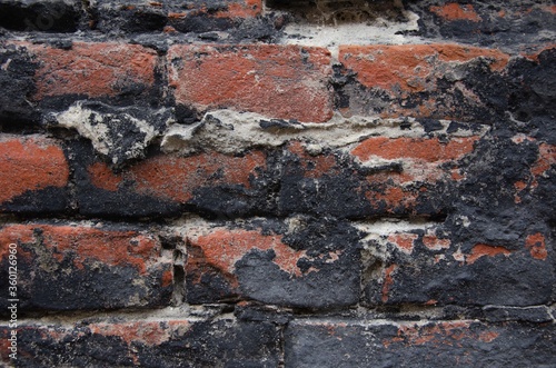 Old brick wall with black peeling plaster background 