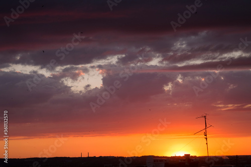 Natural sunset sunrise over the city and meadow. Bright dramatic sky and dark earth, beautiful clouds. Dawn Sunrise. The sun over the horizon, horizon. Warm colors. Beautiful sky.