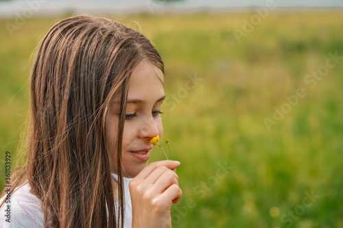 A little girl child gently holds a flower in her hands in the countryside against the background of mountains and f