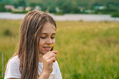 A little girl child gently holds a flower in her hands in the countryside against the background of mountains and f