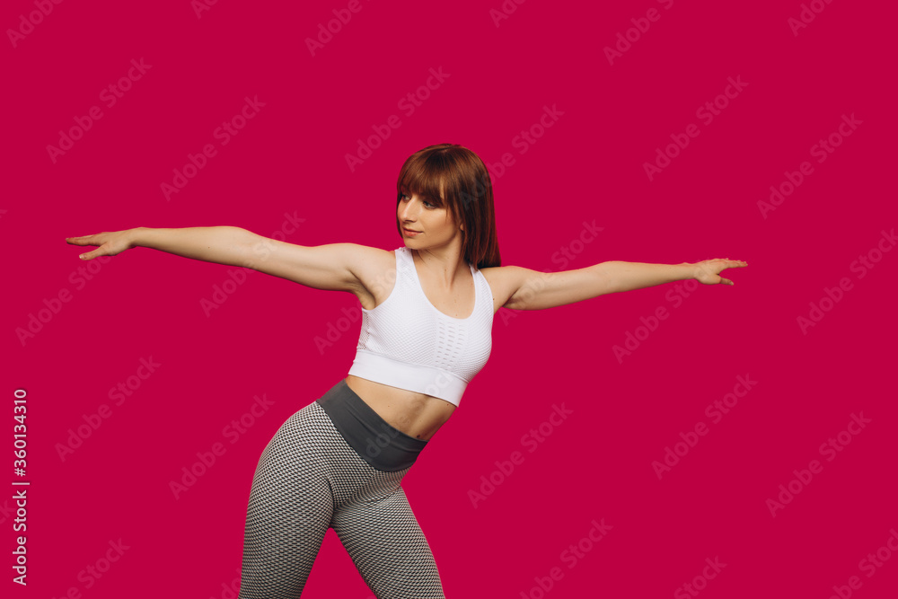 Girl performs fitness exercises on isolated pink background. Girl playing sports. Young girl performs stretching exercises. Sports girl. Place for an inscription.