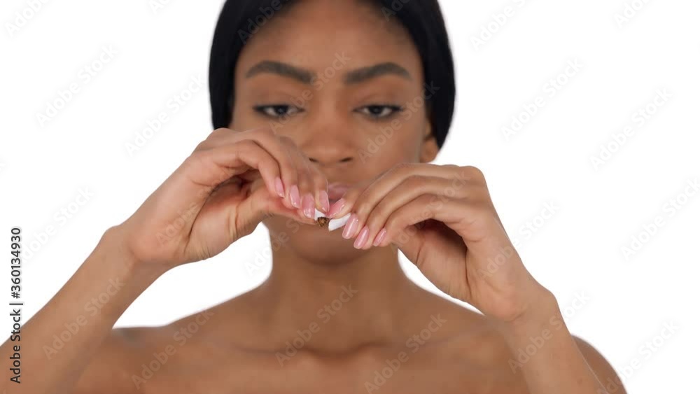Young woman is breaking a cigarette. Quit smoking concept. Isolated over white background Young woman is breaking a cigarette. Quit smoking concept. Isolated over white background