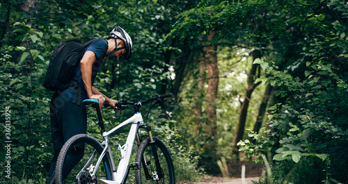 Rear view of professional male cyclist cycling on mountain road on nature background. Male bicyclist riding a bike in the forest outdoor.