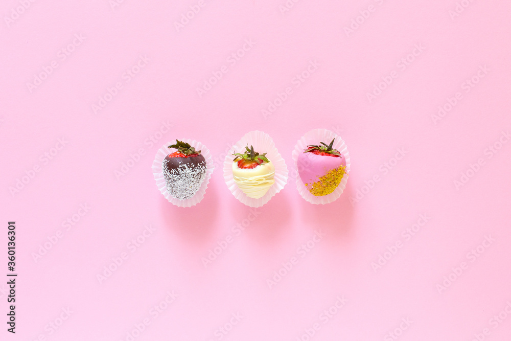 Strawberries covered with chocolate on a pink background. Flat lay fruits composition