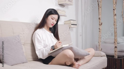 The beautiful woman sitting on the sofa is reading a book. photo