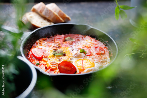 Eggs baked with tomatoes. Ready dish served in a hot pan. Suggestion of serving the dish.