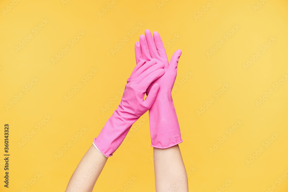 Studio photo of raised two hands touching each other while applying soap on it before washing it, isolated over orange background. Human hands concept