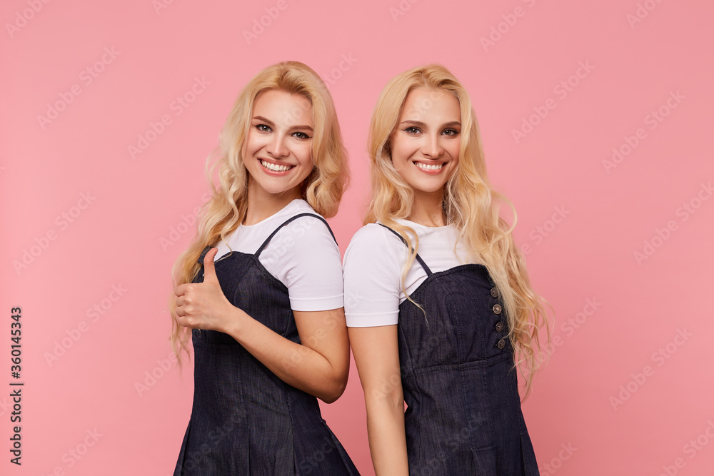 Studio photo of young long haired white-headed ladies showing their white perfect teeth while looking happily at camera with wide smiles, isolated over pink background Studio photo of young long haired white-headed ladies showing their white perfect teeth while looking happily at camera with wide smiles, isolated over pink background