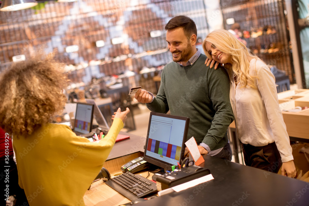Man paying female sales assistant with credit card in clothes shop Man paying female sales assistant with credit card in clothes shop
