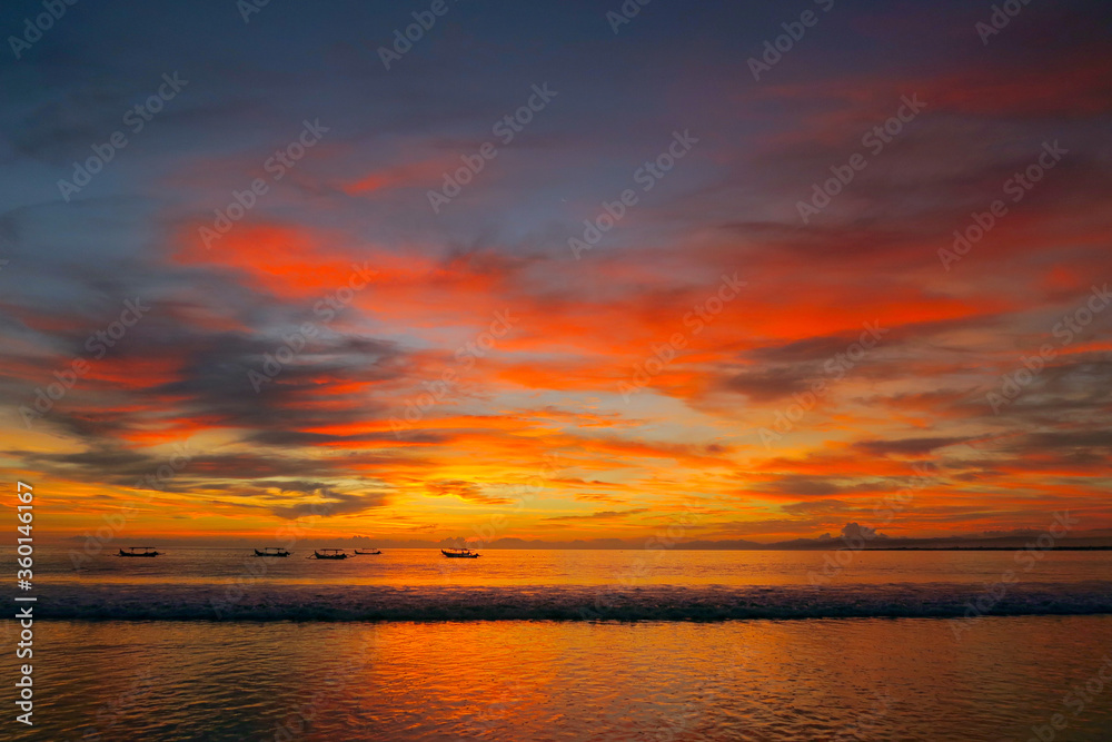 Fishermen boats silhouettes in tropical fiery sunset light at Kuta beach, Bali island, Indonesia 