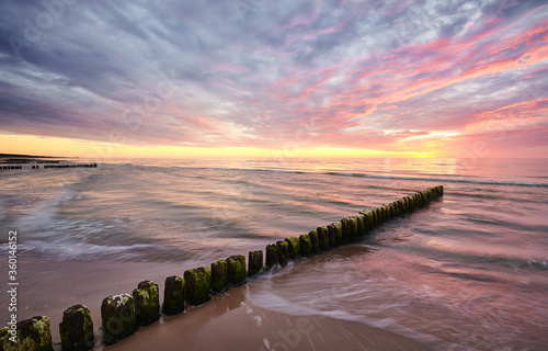 Seascape with an old wooden breakwater at sunset.