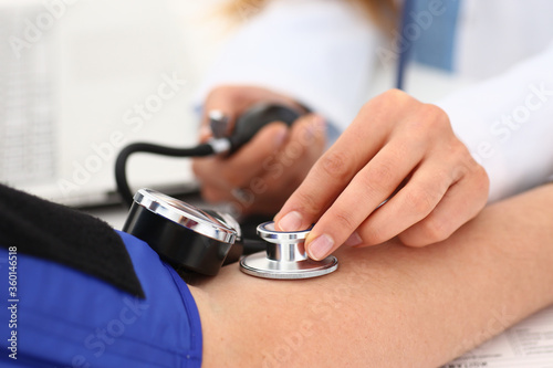 Close up of female physician checking patient blood pressure in clinic