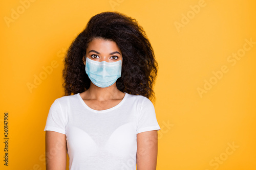 Close-up portrait of her she nice attractive wavy-haired girl wearing safety gauze mask mers cov contamination flue grippe syndrome preventive measures isolated vivid yellow color background © deagreez