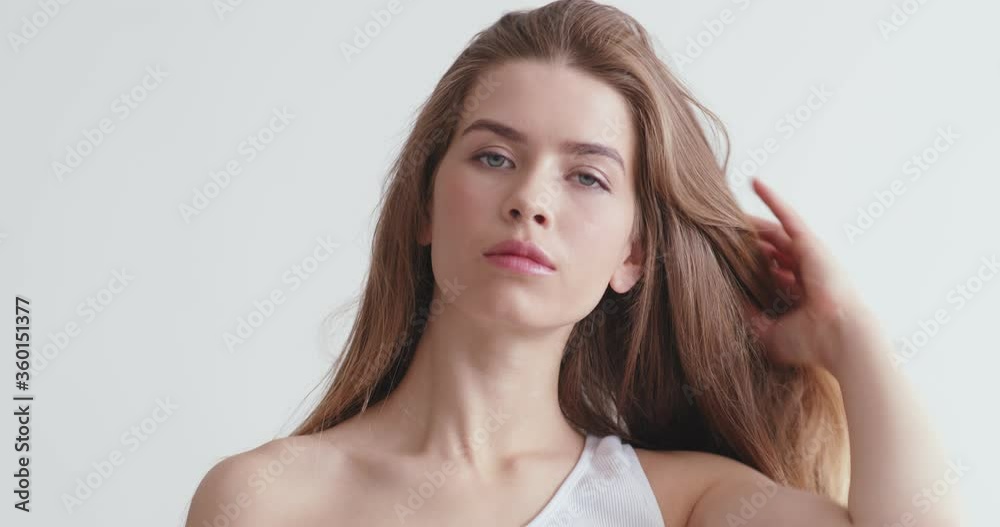 Young woman looking in mirror, fixing her hair Young woman looking in mirror, fixing her hair