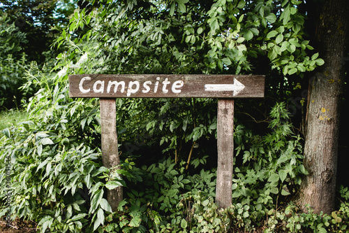 Fototapeta Naklejka Na Ścianę i Meble -  Campsite wooden sign. Tourist outdoor destination arrow. Forest direction information. Summer camp in green park.