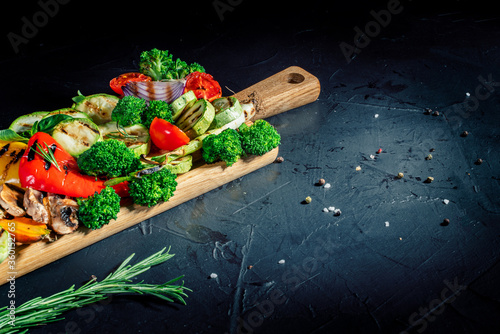 Grilled vegetables and mushrooms with basil and dry herbs on a dark background. Vegan grill concept