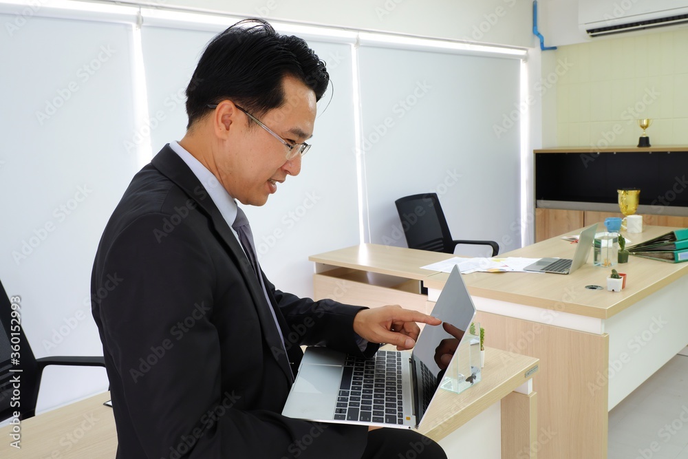 Asian Business people working on notebooks sitting on table Asian Business people working on notebooks sitting on table