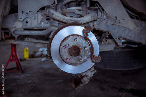 A car mechanic working grinding brake disc with grinding machine and vehicle brake disc turning for disc brake system repair car safety.