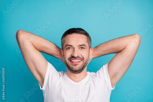 Close-up portrait of his he nice attractive content sporty cheerful cheery bearded guy wearing tshirt holding hands behind head resting isolated over bright vivid shine vibrant blue color background