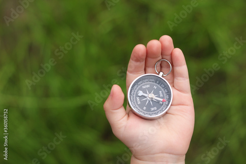 Old classic navigation compass in hand on natural background