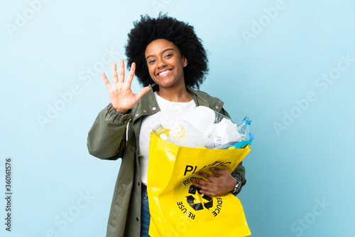 Young African American woman holding a recycle bag isolated on colorful background counting five with fingers