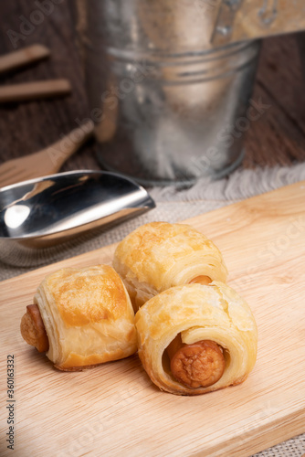Homemade sausage rolls on a wooden plate, mini sausage rolls on wooden plate.