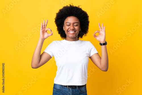 Young African American woman isolated on yellow background in zen pose