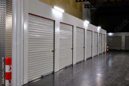 Row of white doors indoor storage units in a self storage facility. Rental Storage Units with red white safety pole. Netherlands