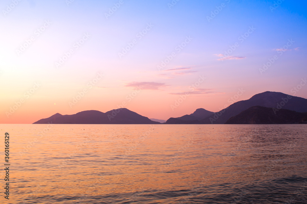 The south coast of Turkey, Mediterranean Sea, Oludeniz, Mugla, Fethiye. Rocky mountains that go to sea. National park, a popular tourist destination, pink sunset in the sea