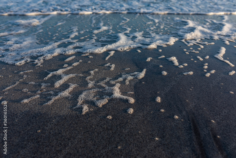 soft waves and sea foam on sandy beach during sunrise soft waves and sea foam on sandy beach during sunrise