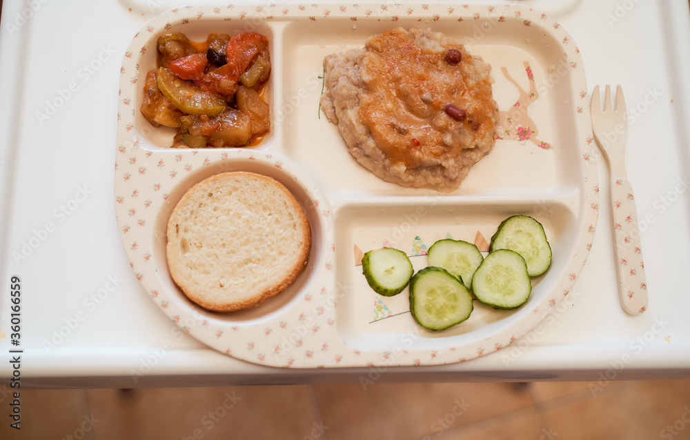 Children's plate in the form of a tray with vegetable stew, steam, bread and cucumbers. Top view Children's plate in the form of a tray with vegetable stew, steam, bread and cucumbers. Top view