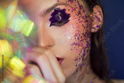 Beautiful young girl with luxurious brilliant purple make-up on a blue background. Good for beauty salons, banners, posters, flyers.