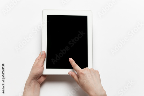 Close up of human hands using tablet isolated on white background. Top view. Copyspace, blank screen. Surfing, online shopping, scrolling, betting, working. Education and business concept.