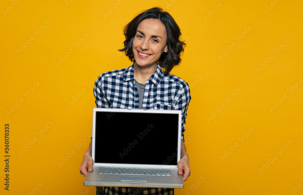 Here is my notebook. Half-length photo of pleased pretty girl in a black and white checkered shirt with her head tilted a little, holding her big gray notebook. Here is my notebook. Half-length photo of pleased pretty girl in a black and white checkered shirt with her head tilted a little, holding her big gray notebook.