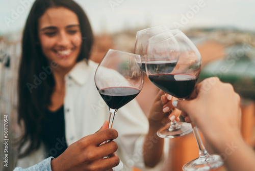 Fototapeta Group of millennial friends toasting wine at rooftop party, Young people laughin