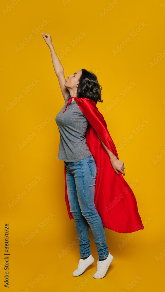 © My Ocean studio - I take off! A young girl, turned sideways, pretending she is a superhero, standing in a classic superhero pose, dressed casually, but with a red superhero fluttering cloak is ready to take off. © My Ocean studio - I take off! A young girl, turned sideways, pretending she is a superhero, standing in a classic superhero pose, dressed casually, but with a red superhero fluttering cloak is ready to take off.