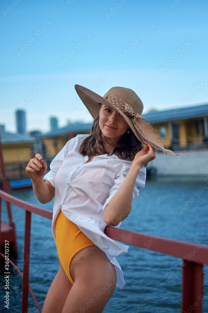 Beautiful girl in a hat , posing on a pier, on a background of water