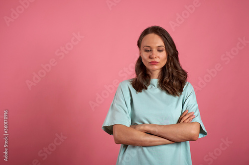 Portrait of a upset girl standing with arms folded over a pink background
