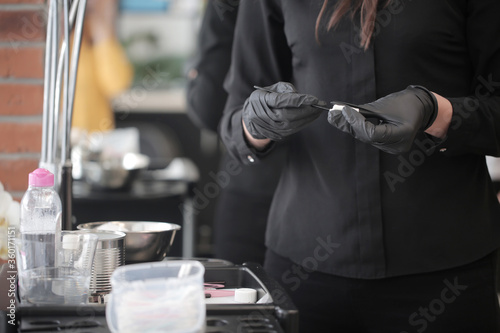 Female hands of a girl in a black uniform clean professional tools after the procedure of permanent makeup of eyebrows in the interior of the salon. Set of hairdressing tools of choice.