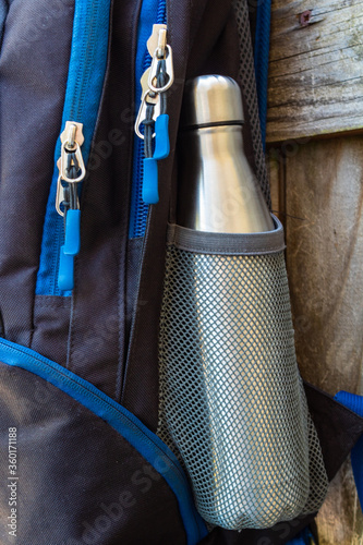 Metal flask, bottle, thermos inside a mesh pocket of a backpack