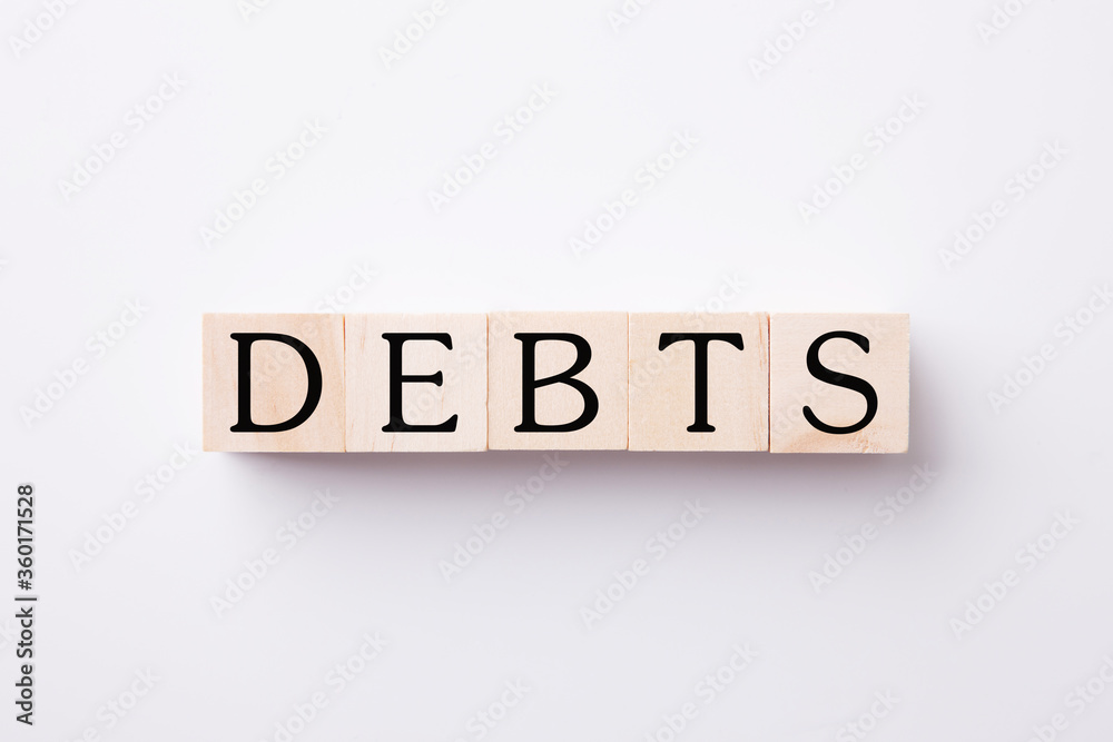 DEBTS text on wood block on White background. DEBTS text on wood block on White background.