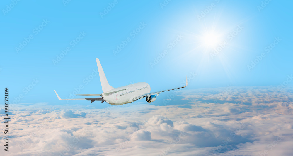 Fototapeta Biały samolot pasażerski w chmurach z promieniami słońca - Podróżuj transportem lotniczym